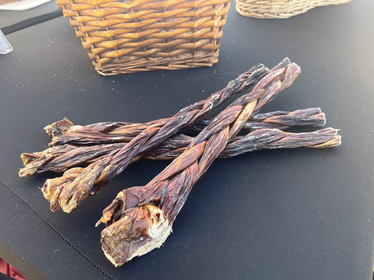 12" Braided beef gullet sticks on a black table with wicker baskets in the background