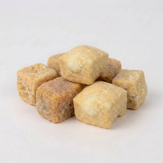 Pile of golden cube-shaped yak cheese puff dog treats on a light background